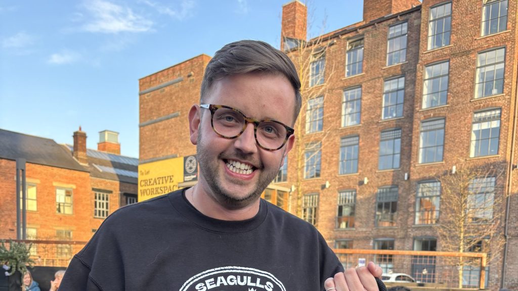 Liam holding a 20th Anniversary Seagulls tote bag.