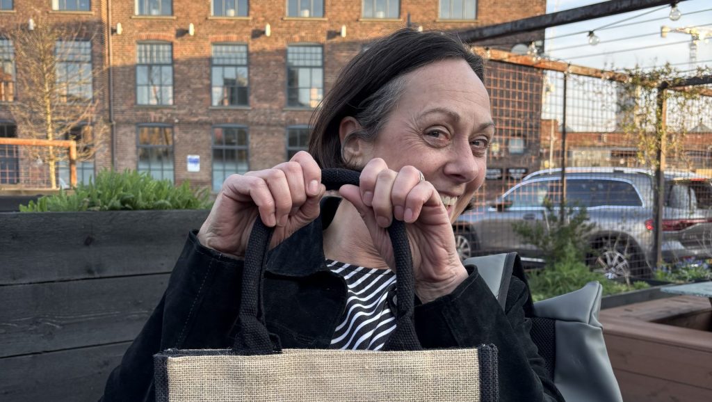 Meg holding a 20th Anniversary Seagulls tote bag.